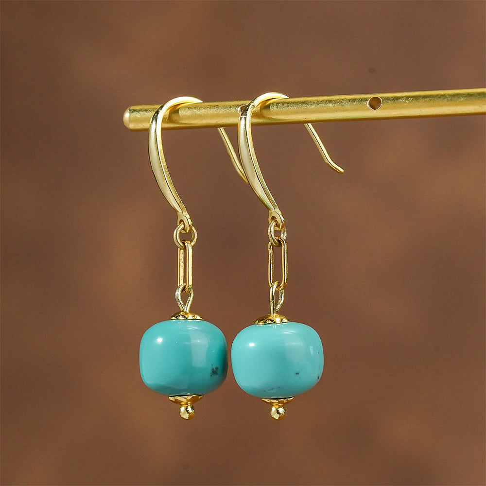Gold plated earrings with smooth turquoise gemstone beads hanging on a brass rod