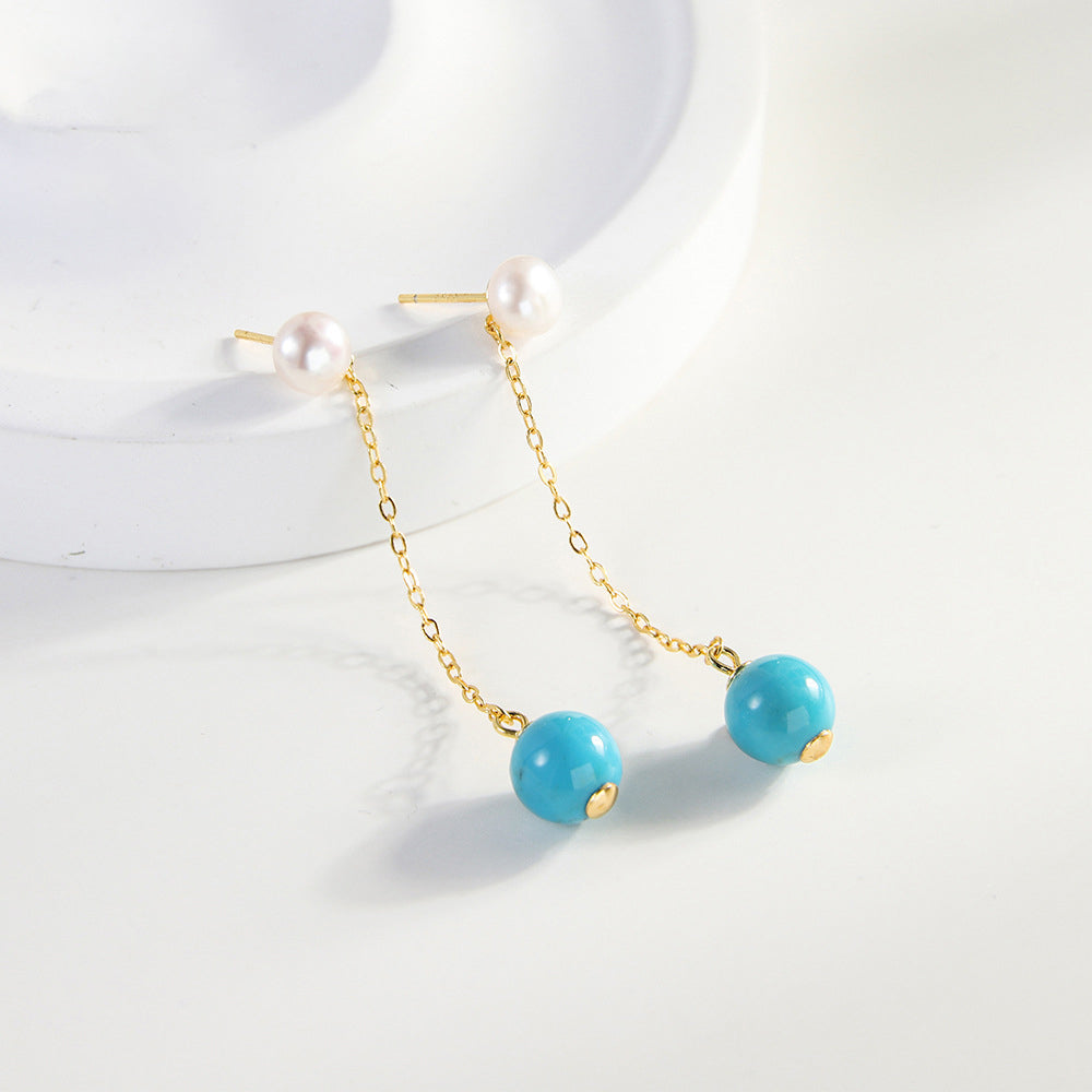 Gold plated dangle earrings with white pearls and turquoise gemstone beads on white background
