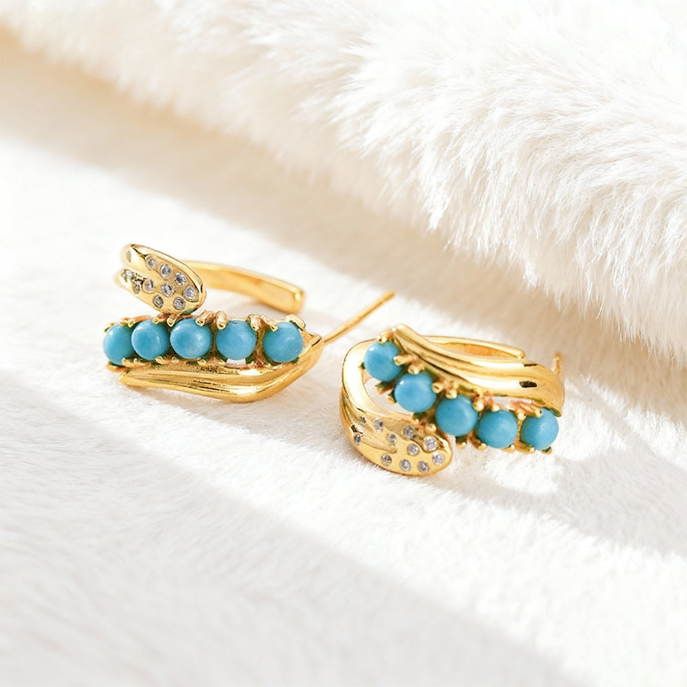 Gold-plated earrings with turquoise beads and small crystal accents on white fabric