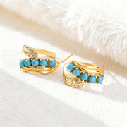 Gold-plated earrings with turquoise beads and small crystal accents on white fabric