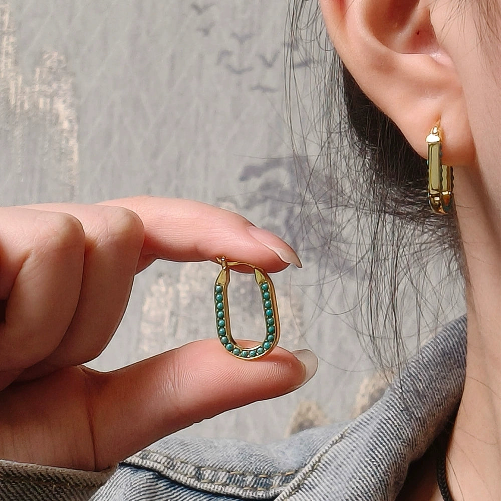 Hand holding gold plated hoop earring with turquoise beads, worn with matching plain gold hoop earring