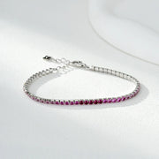 Silver tennis bracelet with a row of small pink gemstones on a white surface