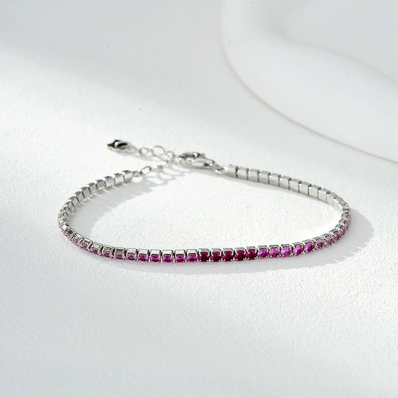 Silver tennis bracelet with a row of small pink gemstones on a white surface