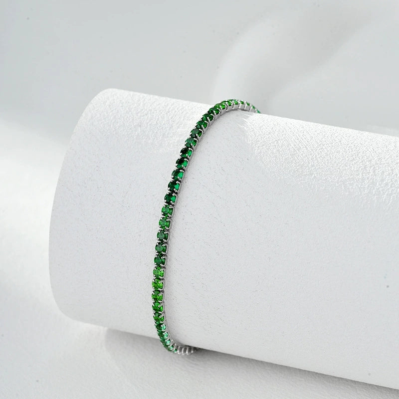 Elegant green gemstone tennis bracelet with gold-plated setting on white display