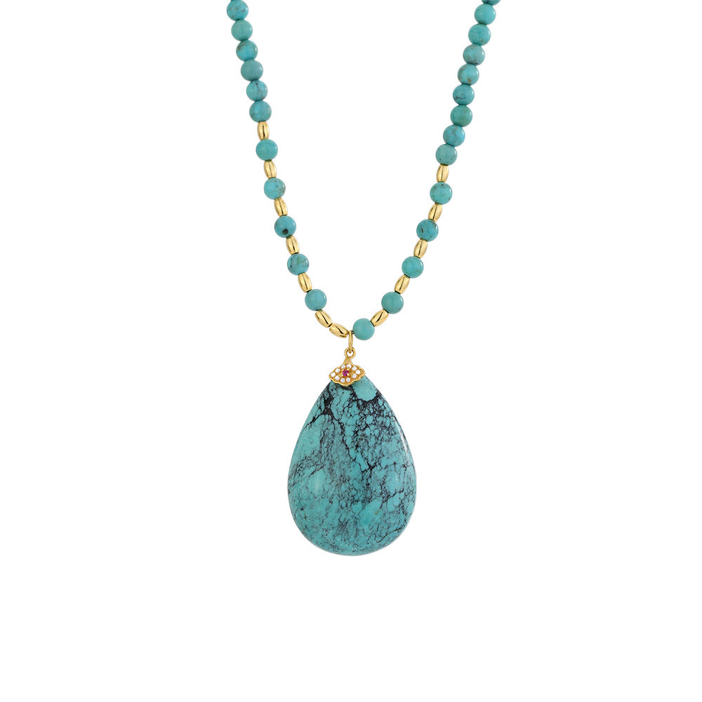 Turquoise beaded necklace with gold accents and a teardrop-shaped turquoise pendant with a small floral gold detail