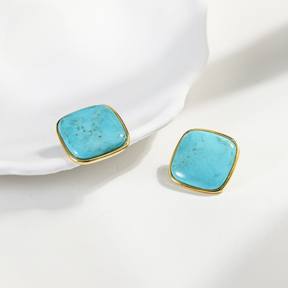 Square turquoise gemstone stud earrings with gold plated setting on white surface