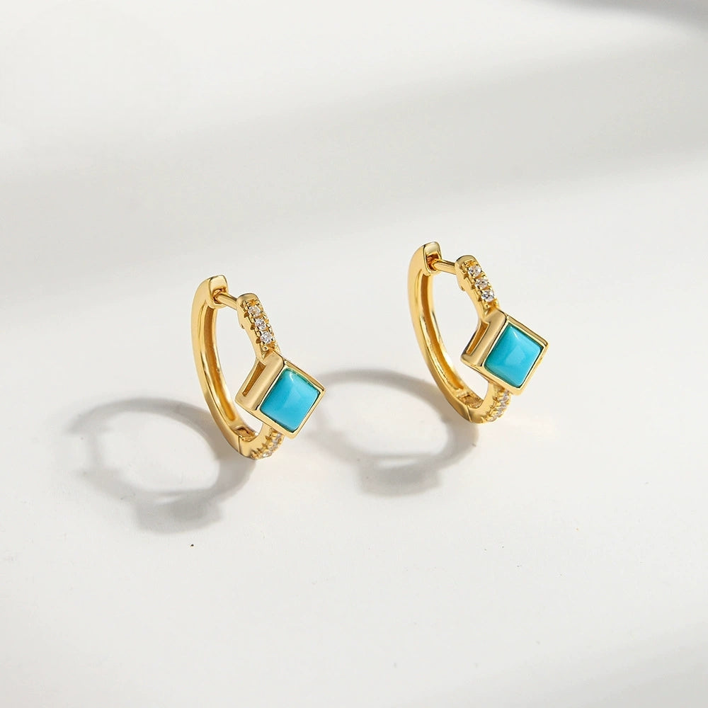 Gold-plated hoop earrings with square turquoise gemstones and small clear crystals on white background
